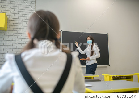 Schoolgirl sitting at the desk and listening to her teacher 69739147