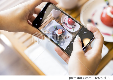 拍蛋糕的照片與智能手機的一個少婦 拍蛋糕的照片與智能手機的一個少婦 69739190