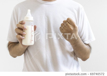 一個男人抱著嬰兒奶瓶,握著拳頭 一個男人抱著嬰兒奶瓶,握著拳頭 69740572