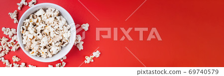 Bowl of popcorn and controller on red background Bowl of popcorn and controller on red background 69740579