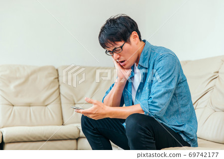 Asian male patient sitting on sofa in waiting room (toothache) Asian male patient sitting on sofa in waiting room (toothache) 69742177