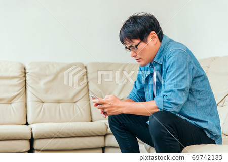 Asian male patient sitting on couch in waiting room Asian male patient sitting on couch in waiting room 69742183