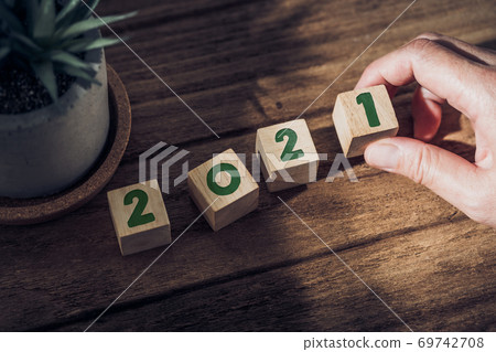 2021 happy new year with hand pick up wood block on wood table with sunlight from window.hope for new year concept 2021 happy new year with hand pick up wood block on wood table with sunlight from window.hope for new year concept 69742708