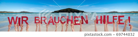 People Hands Holding Word Wir Brauchen Hilfe Mean We Need Help, Ocean Background People Hands Holding Word Wir Brauchen Hilfe Mean We Need Help, Ocean Background 69744832