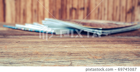 View of pile of different and overlayed magazines on wooden table. Background textures concept. View of pile of different and overlayed magazines on wooden table. Background textures concept. 69745087
