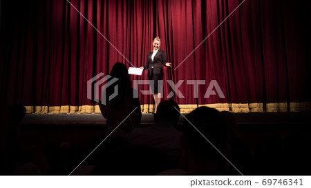 Female caucasian speaker giving presentation in hall at university or business centre workshop 69746341