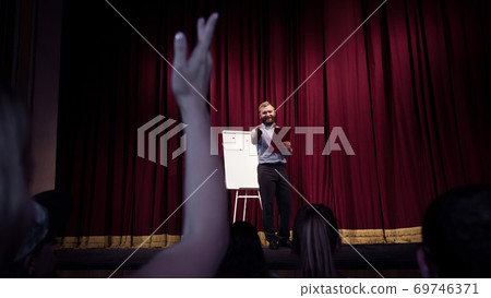 Male caucasian speaker giving presentation in hall at university or business centre workshop 69746371