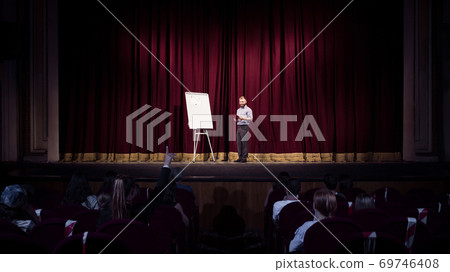 Male caucasian speaker giving presentation in hall at university or business centre workshop 69746408
