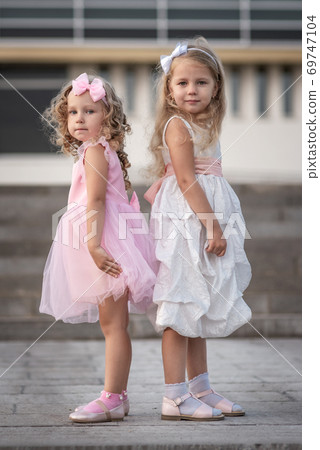 Two little girls in pink and white dressses on the street Two little girls in pink and white dressses on the street 69747104