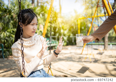 Asian child girl gesturing hand stop with no to drink milk or bored of food, female teenage refused a glass of milk, daughter rejecting when mother try to offer some healthy food, anorexia concept 69747242
