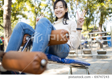 Beautiful asian child girl practicing fitness,doing sit up exercise for health and strength at city park, happy smiling female teenage doing abdominal sit ups in outdoor gym,health care concept 69747243