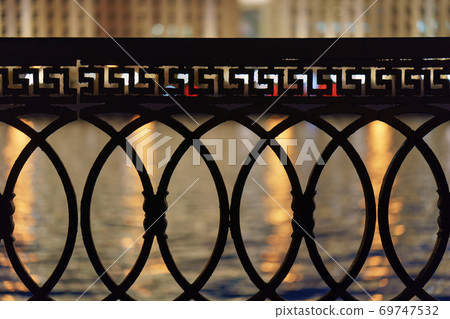 View of Moskva river, city reflections at the water through the metal fence. Concept of the beauty of the Moscow city in night. Buildings across the river. View of Moskva river, city reflections at the water through the metal fence. Concept of the beauty of the Moscow city in night. Buildings across the river. 69747532