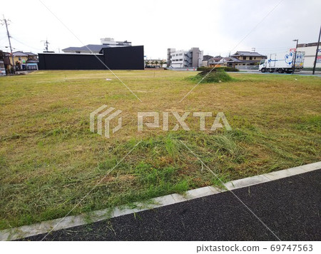 割草後居民區有一片空地和草山，一輛卡車停在右側 69747563