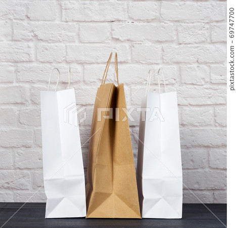 white and brown paper bags with handles on white brick wall background 69747700