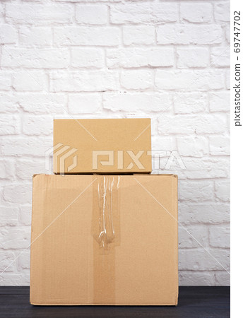 rectangular box made of brown corrugated cardboard on a white brick wall background 69747702