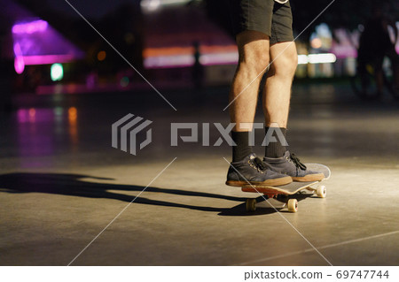 Photography of skateboarder's legs, shoes and skate in night park. Skateboarder getting ready to do the trick to jump. Sportive lifestyles of youth. Dangerous risk speed sports. Photography of skateboarder's legs, shoes and skate in night park. Skateboarder getting ready to do the trick to jump. Sportive lifestyles of youth. Dangerous risk speed sports. 69747744