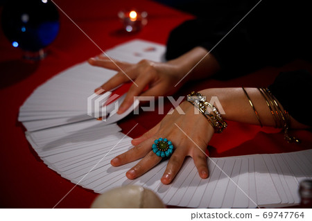 Fortune teller with left hand full of ornament uses tarot card to predict the fate or destiny of people. Fortune teller with left hand full of ornament uses tarot card to predict the fate or destiny of people. 69747764