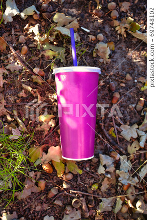 paper soft drink cup with plastic lid and straw thrown in the forest on the ground, milkshake or soda paper cup in nature, blank space for text paper soft drink cup with plastic lid and straw thrown in the forest on the ground, milkshake or soda paper cup in nature, blank space for text 69748102