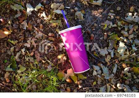 paper soft drink cup with plastic lid and straw thrown in the forest on the ground, milkshake or soda paper cup in nature, blank space for text paper soft drink cup with plastic lid and straw thrown in the forest on the ground, milkshake or soda paper cup in nature, blank space for text 69748103