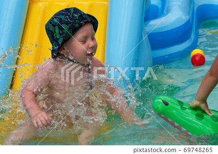 Small child splashes in the water in the pool Small child splashes in the water in the pool 69748265