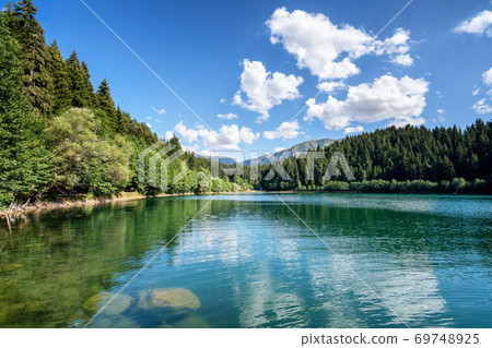 Beautiful view of a lake with pluffy cloudy sky and mountain background. Travel Tourism concept. 69748925
