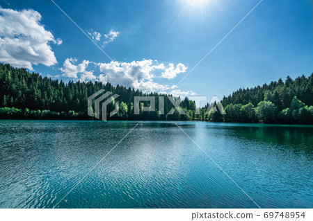 Beautiful view of a lake with white pluffy cloudy sky and mountain background. Travel Tourism concept. 69748954
