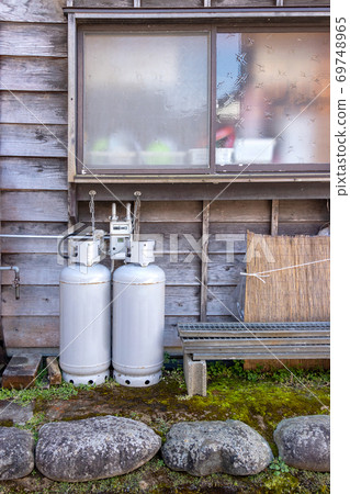 gas bottles standing outside wall near window of house for heating and cooking 69748965