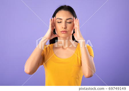 Portrait of young woman holding fingers on temples 69749149