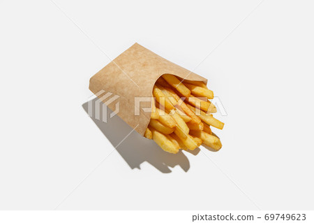 French fries and fast food takeaway in menu during pandemic. Fried potatoes in ecological paper packaging with shadow French fries and fast food takeaway in menu during pandemic. Fried potatoes in ecological paper packaging with shadow 69749623