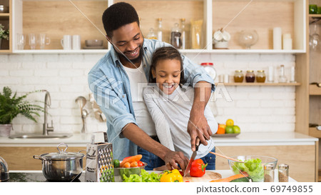 Cute little girl enjoying cooking dinner with lovely daddy Cute little girl enjoying cooking dinner with lovely daddy 69749855