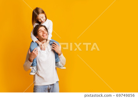Happy father carrying his cheerful little daughter on shoulders 69749856