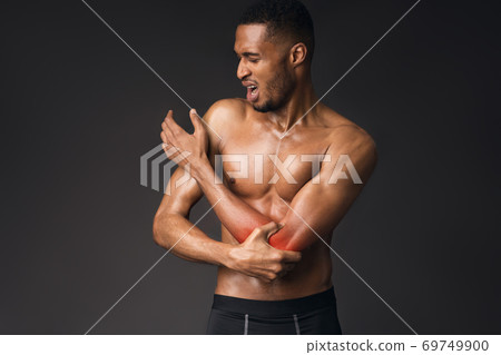 Handsome shirtless black man suffering from pain in hand Handsome shirtless black man suffering from pain in hand 69749900