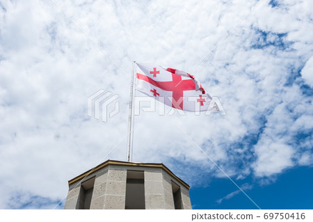 The flag of the Georgia with blue sky and clouds 69750416