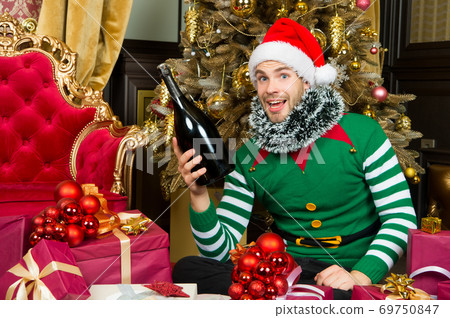 Man in santa hat smile with champagne bottle 69750847