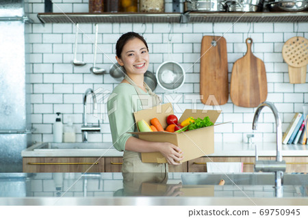 Housewife with an apron standing in the kitchen 69750945