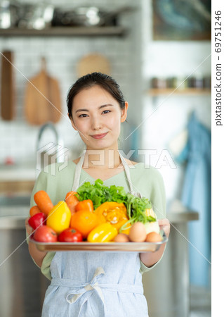A woman holding a vegetable in the kitchen 69751246