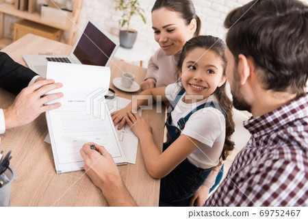Man with wife and daughter signs sales contract. Man with wife and daughter signs sales contract. 69752467