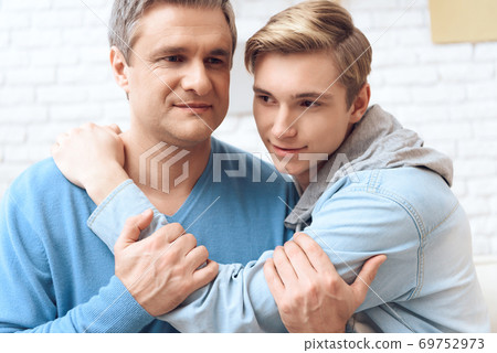 Son hugs beloved dad who holds his hand. 69752973
