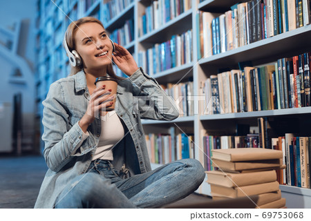 Beautiful girl looks away while sitting in library Beautiful girl looks away while sitting in library 69753068