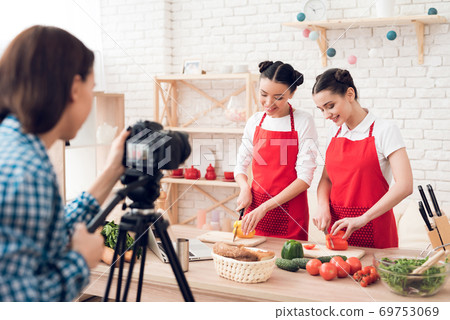 Two happy culinary bloggers dicing peppers. Two happy culinary bloggers dicing peppers. 69753069