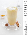 a glass of curcuma latte with glass tube on white table closeup 69753142