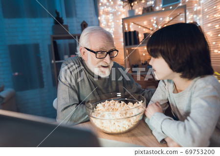 Grandfather with glasses looks at his grandson. Grandfather with glasses looks at his grandson. 69753200