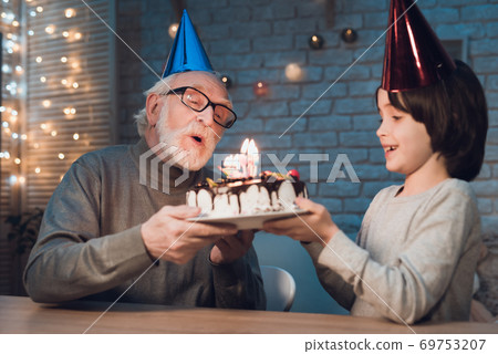 Grandson holds cake for grandfather. Grandson holds cake for grandfather. 69753207
