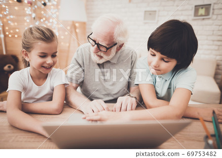 Grandfather with grandchildren sitting at laptop. 69753482