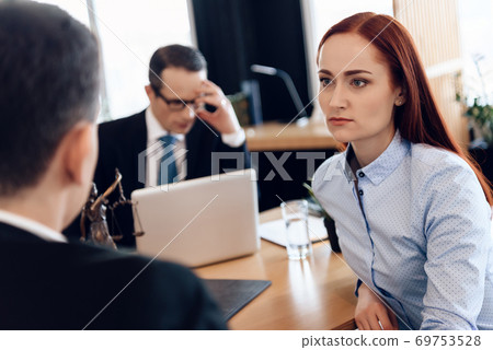 A woman with red hair sits at a table.  69753528