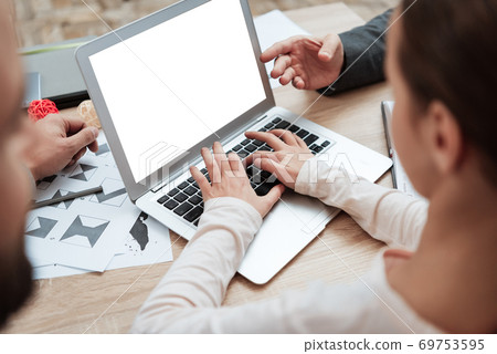 Girl typing while sitting at a desk in the office. Girl typing while sitting at a desk in the office. 69753595