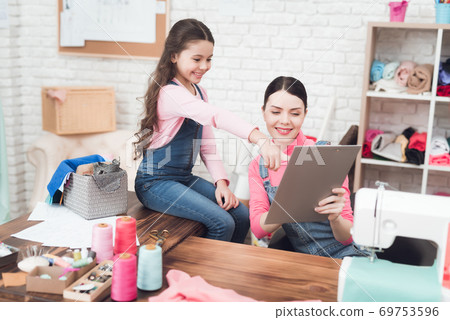 Mom and daughter are looking together at folder. Mom and daughter are looking together at folder. 69753596
