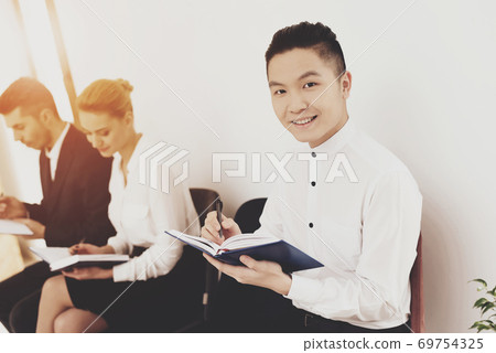 A man in a shirt looks at the camera and writes. A man in a shirt looks at the camera and writes. 69754325