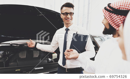 Seller shows Arab that under the hood of a car. Seller shows Arab that under the hood of a car. 69754326
