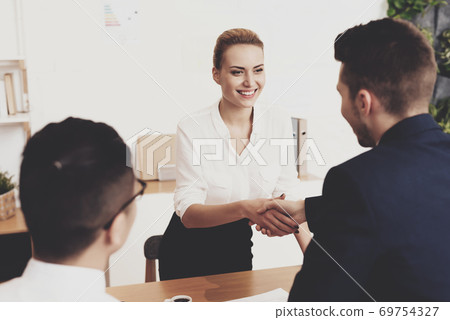 Woman shakes hands with man and thanks for hiring. Woman shakes hands with man and thanks for hiring. 69754327
